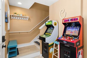 A hallway with a staircase, a blue bench, and two arcade machines. - Oceanside,Pool,Skee-ball,Nintendo,Pets,Beach Gear (Ocean City)