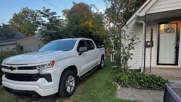 Een witte pickup geparkeerd in een gazon met huisnummer 101.