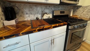 Una cucina con mobili bianchi, un forno a microonde, un fornello a gas e una macchina da caffè.