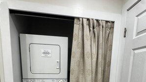 Una lavanderia compatta con lavatrice e asciugatrice, una tenda e una porta.
