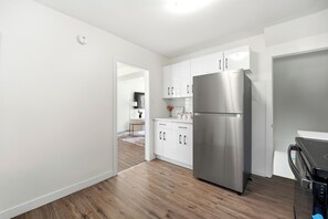 Una cocina moderna con armarios blancos, un refrigerador de acero inoxidable y piso de madera.