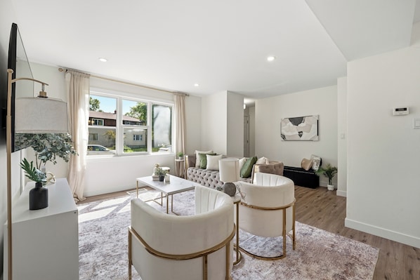 A modern living room with a sofa set, a coffee table, and a dining table.