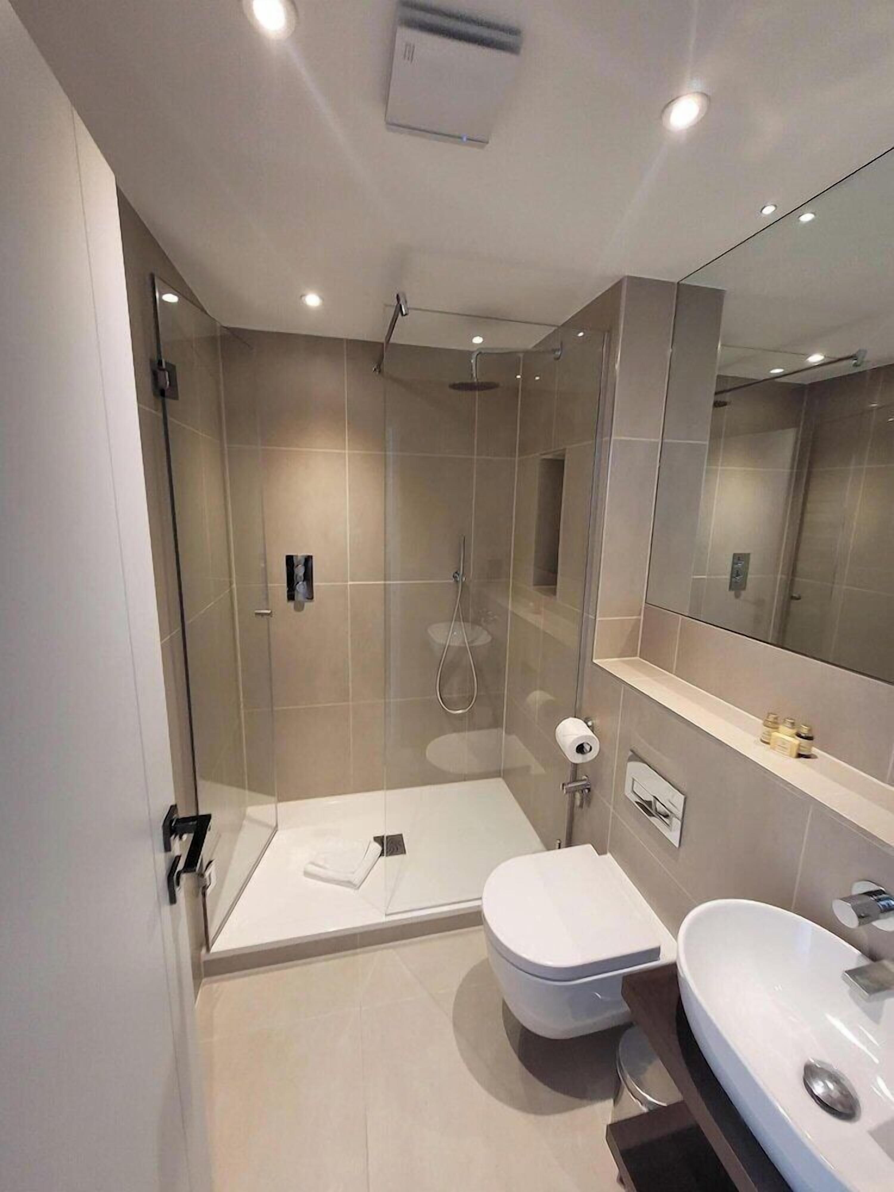 A modern bathroom with a glass-enclosed shower, a white toilet, and a sink.
