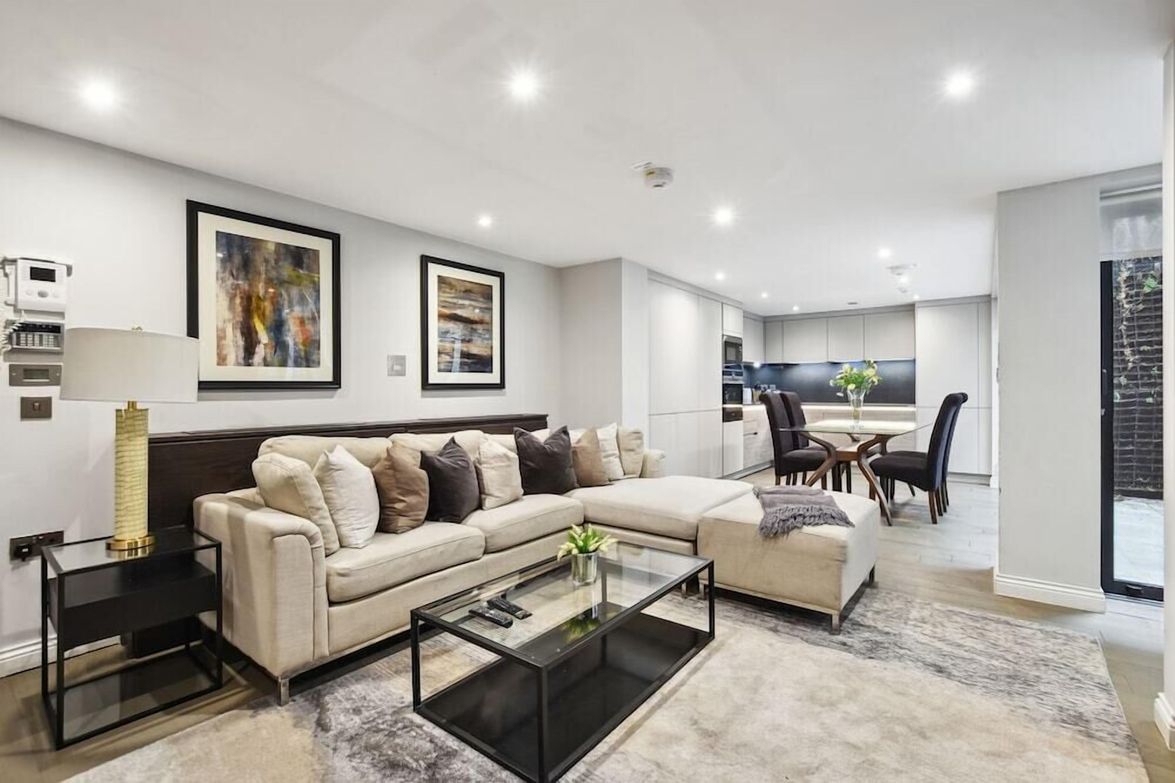 A modern living room with a sectional sofa, a glass coffee table, and a dining area with a table and chairs.