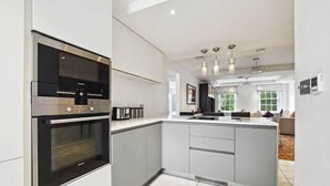 A modern kitchen with built-in appliances, a central island, and pendant lighting. - Buckingham Palace Residences by Aeria Apartments (London)