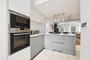 A modern kitchen with built-in appliances, a central island, and pendant lighting.