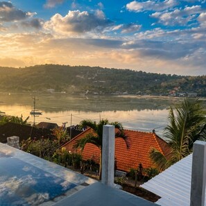 A view of a river with boats, a distant shoreline with buildings, and a red-roofed structure in the foreground. - Dutha Nusa Seaview Private Villas  (Lembongan)