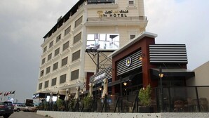 Un hôtel avec une enseigne bien visible, plusieurs étages et des tables en plein air.