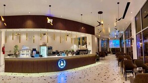 Un espace d’accueil moderne doté d’un comptoir incurvé, d’un coin salon et d’une grande fenêtre.