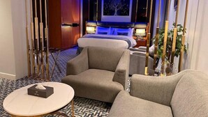 Une chambre d’hôtel avec un lit, deux fauteuils, une petite table et un téléviseur.
