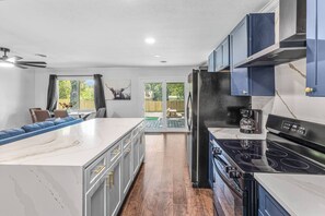 A modern kitchen with a large island, built-in appliances, and a view to the outdoors. - Euless 4BR Home - Mini Golf, Hot Tub & Arcade - Near DFW Airport (Euless)