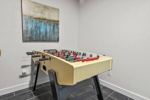 A foosball table in a room with a plain wall and a painting. - Euless 4BR Home - Mini Golf, Hot Tub & Arcade - Near DFW Airport (Euless)