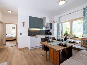 A modern kitchen with a dining area, wooden flooring, and a view of greenery outside. - Eberharter am Schweinberg by Interhome (Mayrhofen)