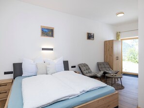 A bedroom with a bed, two chairs, a wardrobe, and a wall-mounted light fixture. - Eberharter am Schweinberg by Interhome (Mayrhofen)
