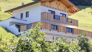 Una moderna casa a due piani con tetto inclinato, ringhiere in legno e facciata bianca.