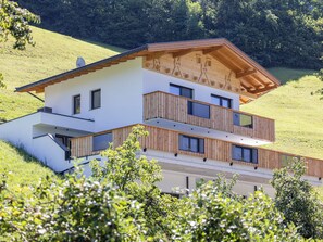Ein modernes, zweistöckiges Haus mit geneigtem Dach, Holz-Balkonläufen und weißer Fassade.