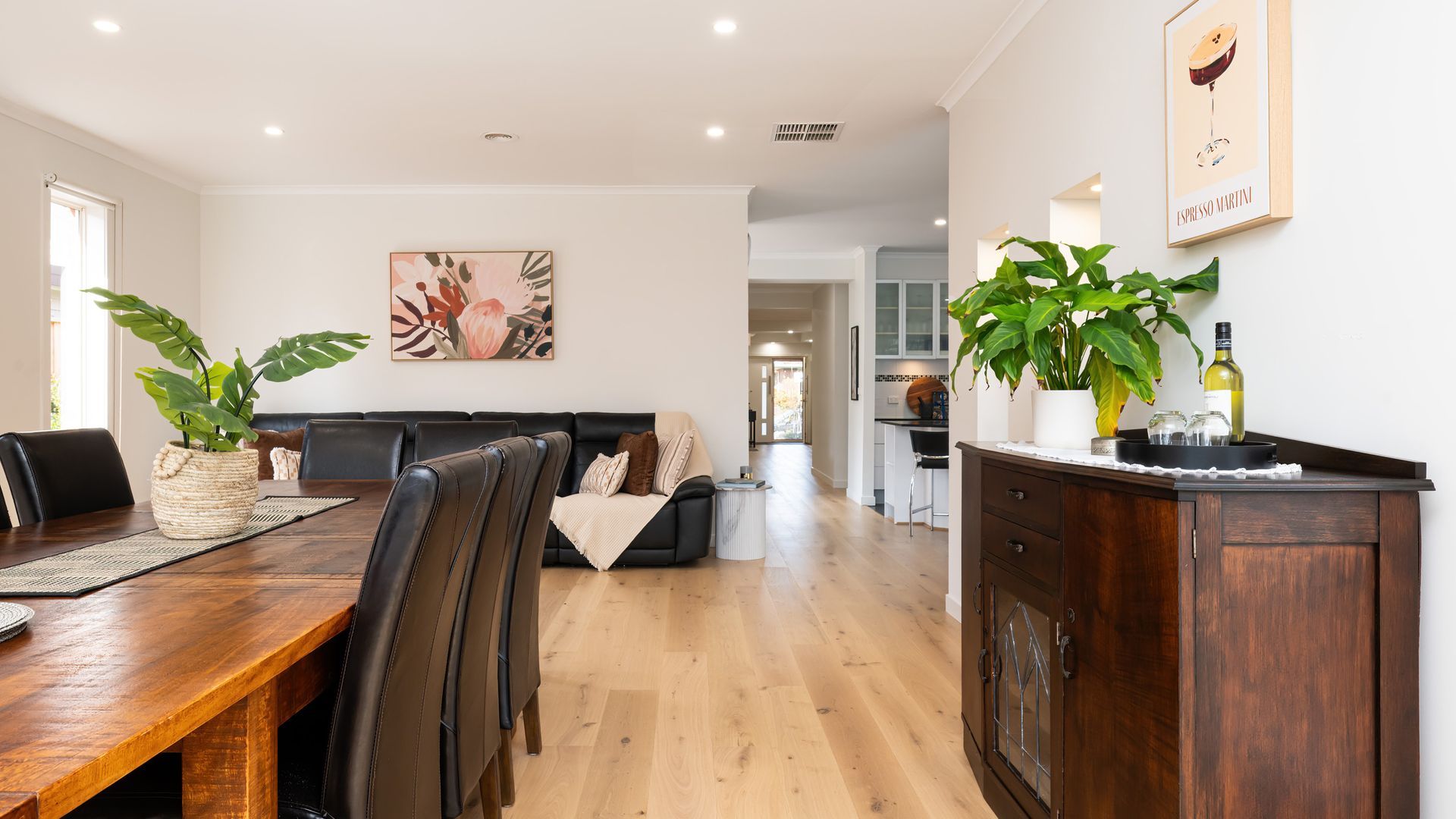 A modern living space with a dining area, a sofa, and a kitchen.