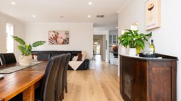 A modern living space with a dining area, a sofa, and a kitchen.