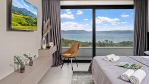 Ein modernes Hotelzimmer mit einem großen Fenster, das einen malerischen Blick auf Berge und einen See bietet.