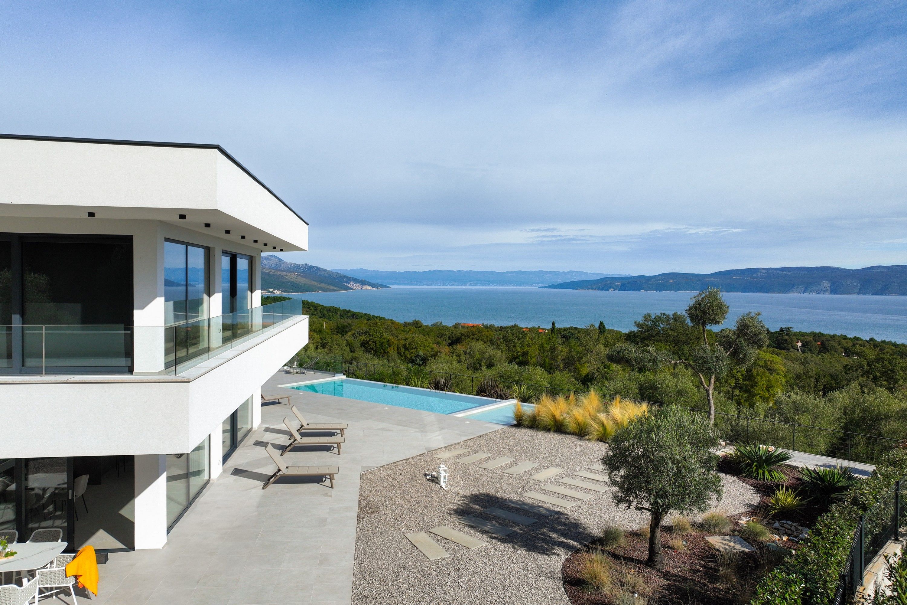Un bâtiment moderne doté d’une piscine et offrant une vue sur un lac et des montagnes.