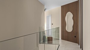 Ein modernes Interieur mit Glastrennwand, Wandverkleidung aus Holz und einer Tür mit ungewöhnlicher Form.