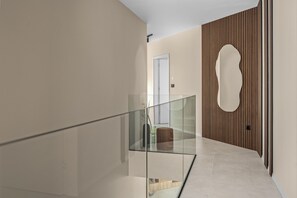 Ein modernes Interieur mit Glastrennwand, Wandverkleidung aus Holz und einer Tür mit ungewöhnlicher Form.