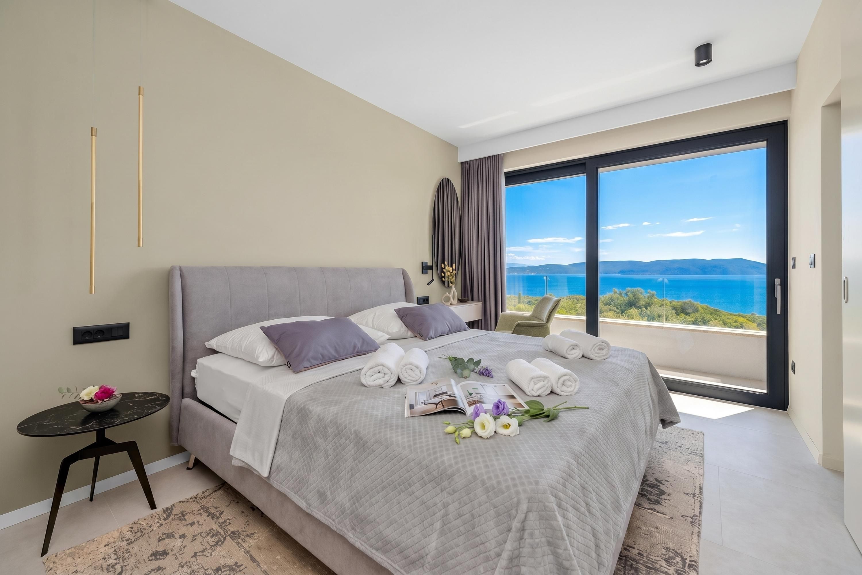 Une chambre moderne avec un grand lit, une petite table et une vue sur la mer.