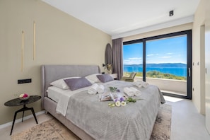 Une chambre moderne avec un grand lit, une petite table et une vue sur la mer.