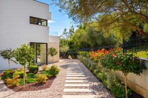 A modern building with a gravel pathway leading to a glass door entrance. - Villa Alba (Rasa)