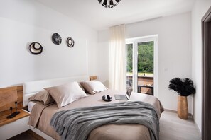 A modern bedroom with a bed, a laptop, and a view of a balcony with greenery. - Villa Terra With Pool & Sauna Near Rabac (Labin)