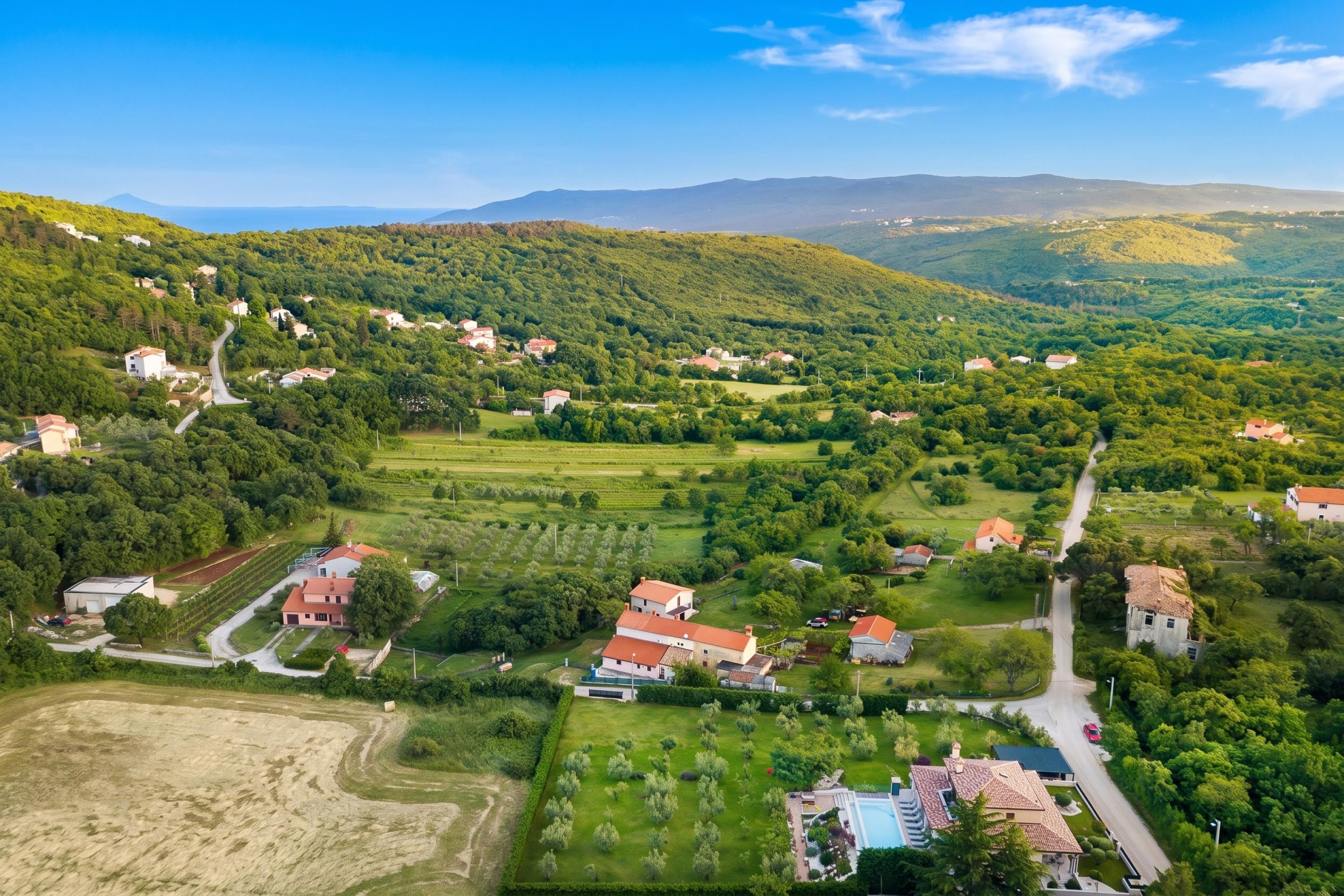 A rural landscape with scattered houses, fields, and a road.