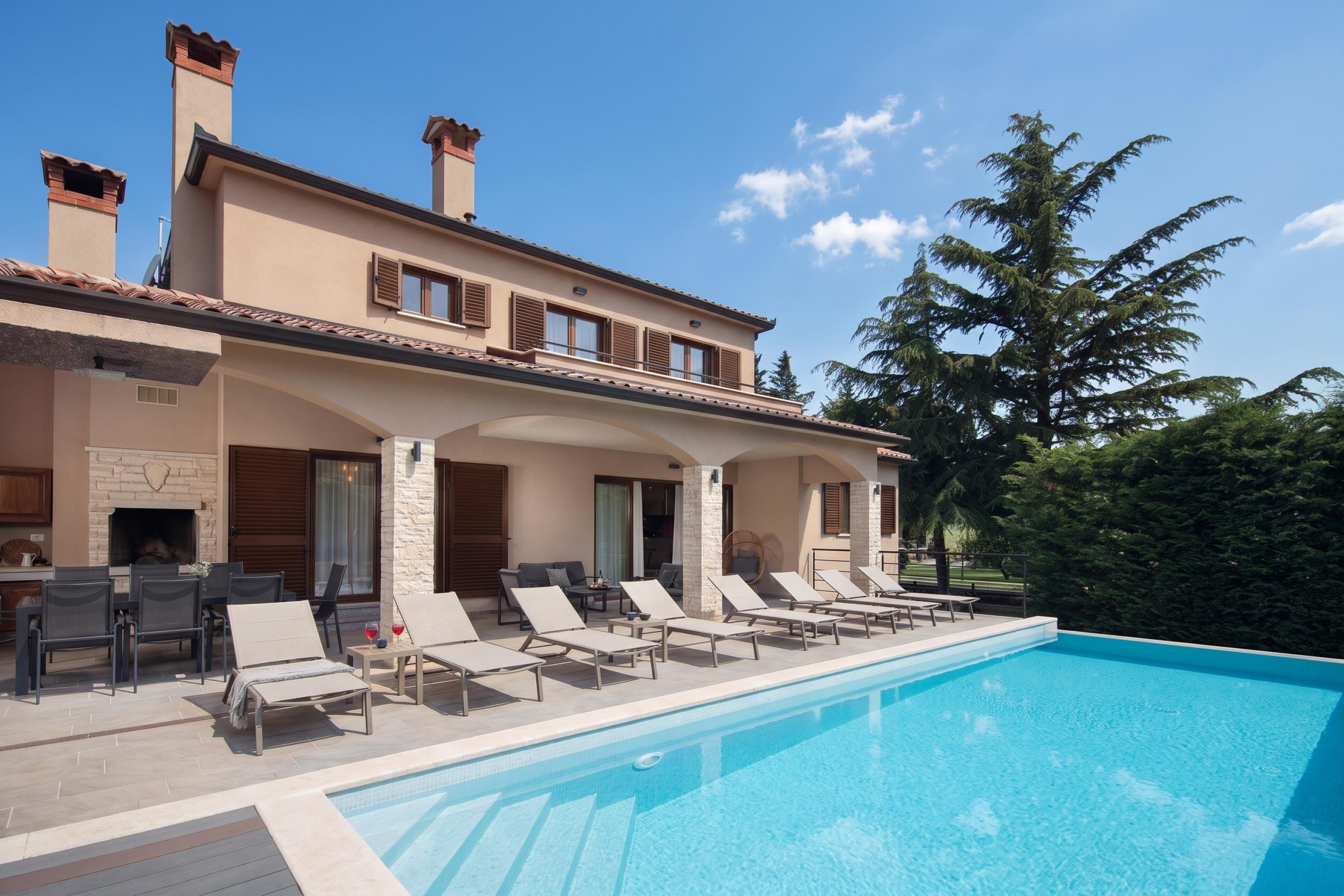 A two-story building with a swimming pool, outdoor seating, and a stone fireplace.
