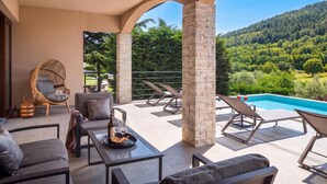 A terrace with outdoor seating, a pool, and a view of a forested hillside. - Villa Terra With Pool & Sauna Near Rabac (Labin)
