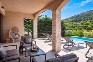 A terrace with outdoor seating, a pool, and a view of a forested hillside. - Villa Terra With Pool & Sauna Near Rabac (Labin)