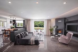 A modern living room with a sofa, a pink armchair, a fireplace, and a television. - Villa Terra With Pool & Sauna Near Rabac (Labin)
