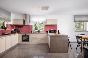 A modern kitchen with a central island, built-in appliances, and a view of greenery outside. - Villa Terra With Pool & Sauna Near Rabac (Labin)