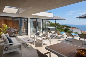 A modern outdoor living area with a pool, lounge chairs, and a wooden table. - Villa Saturea With Pool & Sauna Near Rabac (Labin)