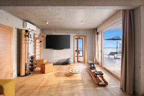 A modern living room with a large TV, exercise equipment, and a view of the outdoors.