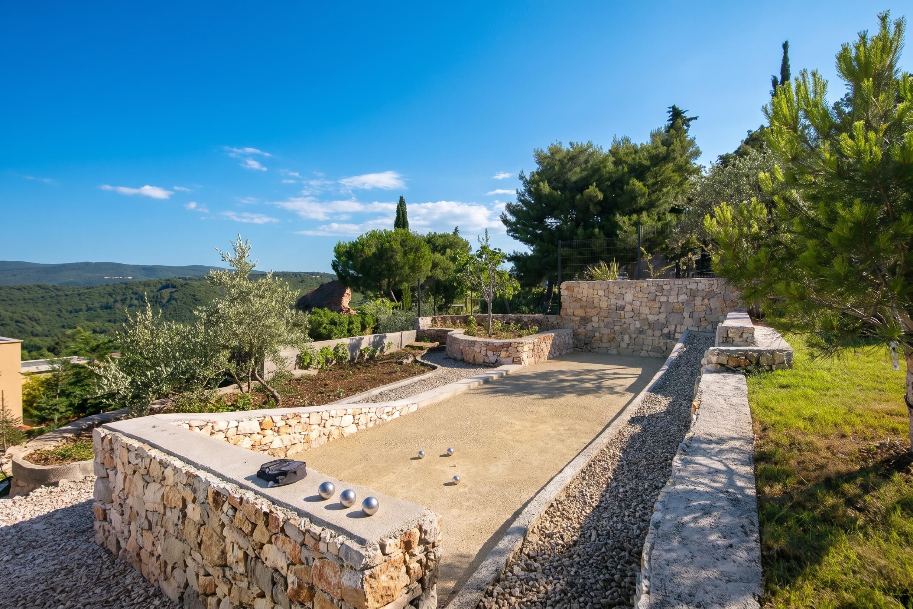 A stone patio with a pool, surrounded by trees and a view of the countryside.
