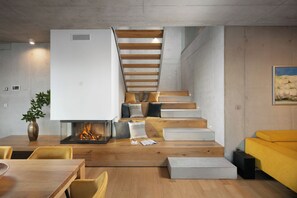 A modern interior with a fireplace, wooden staircase, and a yellow sofa.
