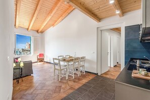 Un comedor con techo de madera, vistas a través de una ventana y una cocina con encimera negra.