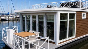 A houseboat with a deck, a table, and chairs. - Enjoy in the harbor at Veerse Meer. (Wolphaartsdijk)