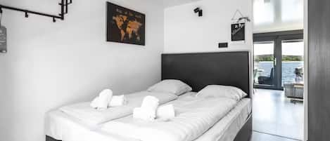 A modern hotel room with a large bed, a world map on the wall, and a view of the outdoors.