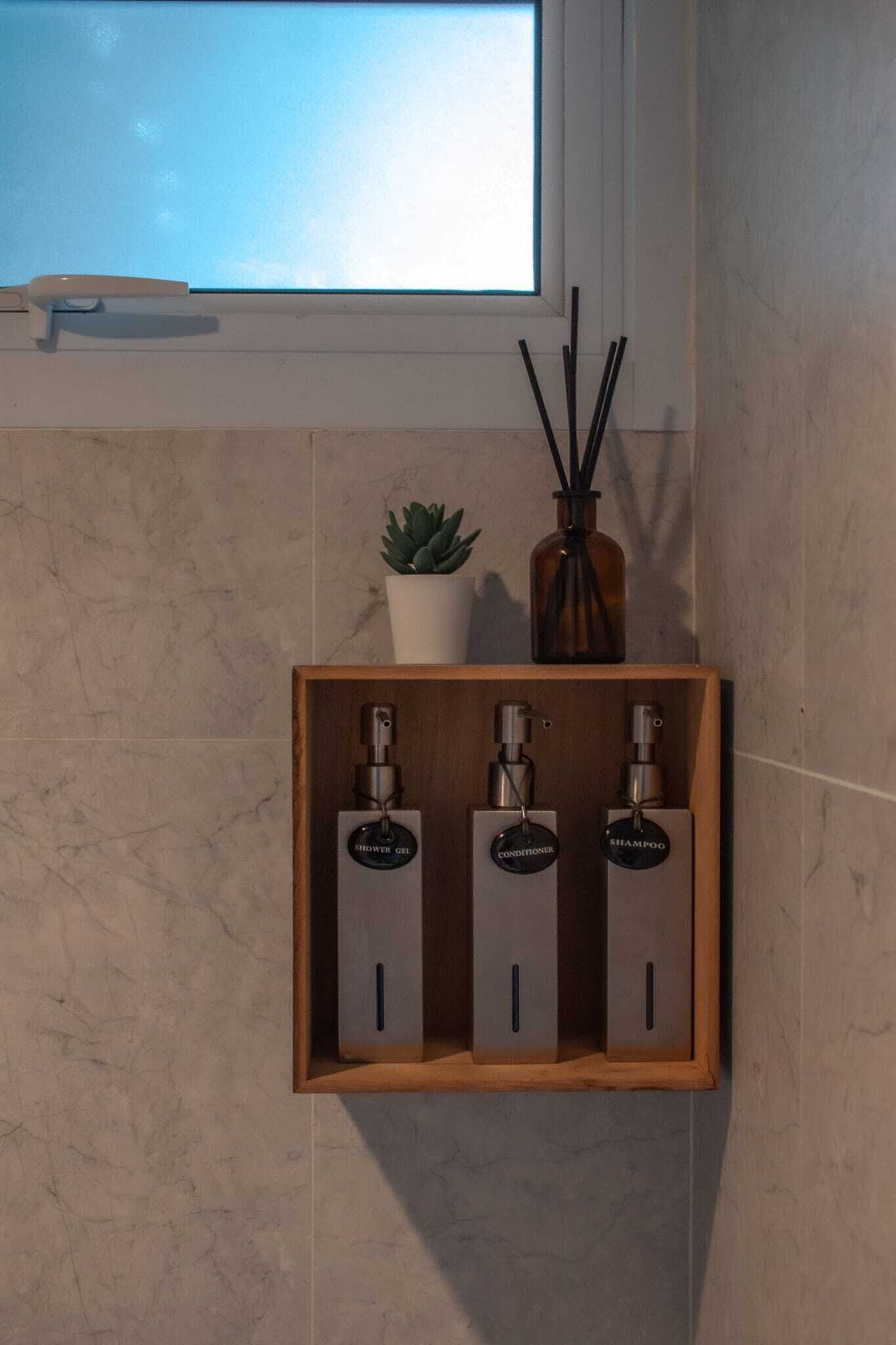 A bathroom with a wooden medicine cabinet containing three bottles labeled 'shower gel,' 'conditioner,' and 'shampoo.'