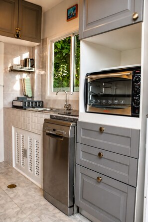 Una cucina compatta con forno integrato, lavastoviglie e finestra che permette l'illuminazione naturale.