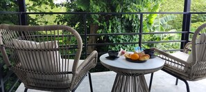 A wicker chair and table set on a balcony with a view of lush greenery. - Baan Chang Retreat - Luxury Private Pool Villa (Bo Phut, Ko Samui)