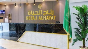 A reception desk with a modern design, featuring a logo and the name 'RETAJ ALHAYAT' in gold lettering. - Retaj Hotel (Makkah)