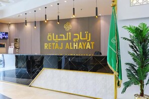 Un mostrador de recepción de diseño moderno, con un logotipo y el nombre 'RETAJ ALHAYAT' en letras doradas.