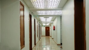 A hotel corridor with a patterned ceiling, wooden doors, and a tiled floor. - Retaj Hotel (Makkah)