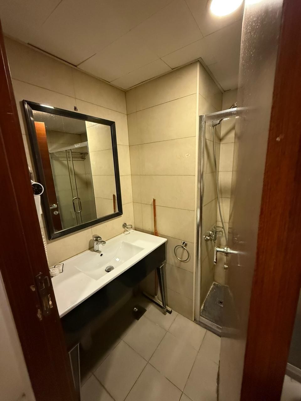A bathroom with a sink, mirror, and shower.